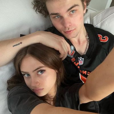 Aris has her hand over her head as they are lying down and taking this selfie.